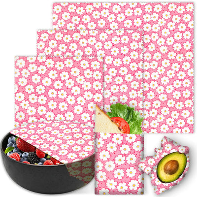 Set of pink cherry blossom reusable food wraps with a bowl of fruit and a sandwich.