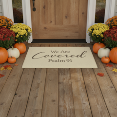 Tan door mat with We Are Covered Psalm 91 printed on the front