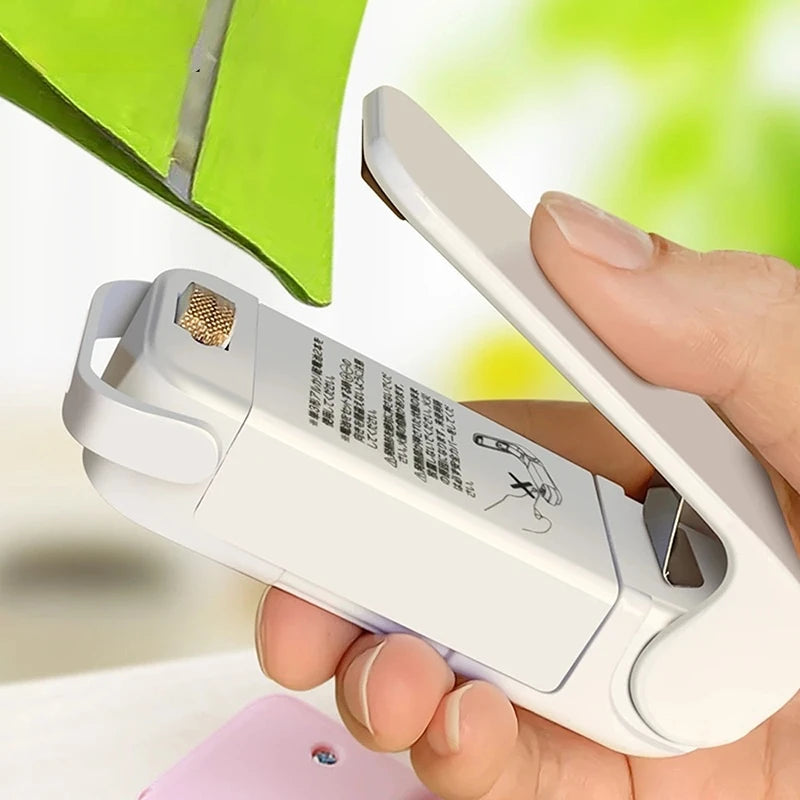 Person holding a white mini resealer device with a blurred green background