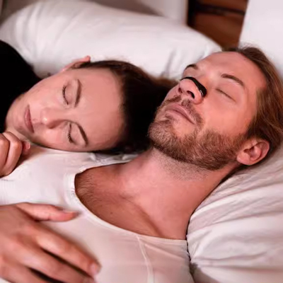Couple sleeping peacefully in bed man wearing a nasal dialator to prevent snoring