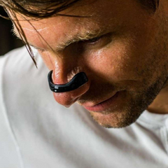 Close-up of a man wearing a black nasal dialotor, perspiring as if just worked out